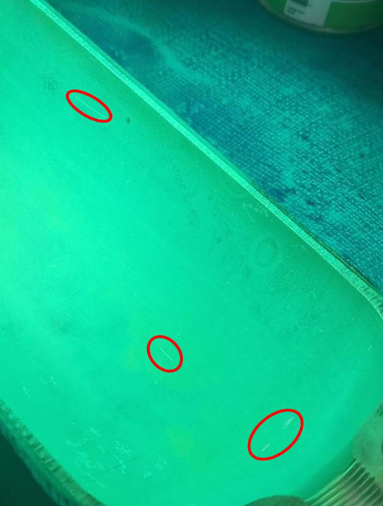Test surface under UV light showing three penetrant-revealed damage areas
